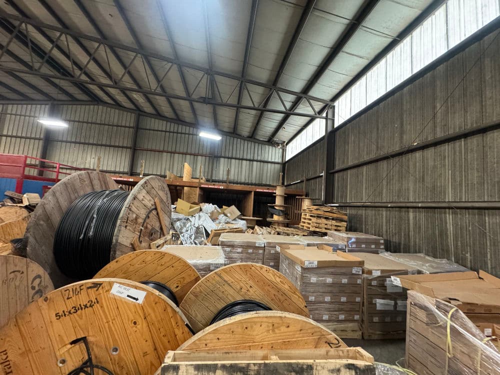 Warehouse interior with large wooden spools of wire and stacked cardboard boxes.
